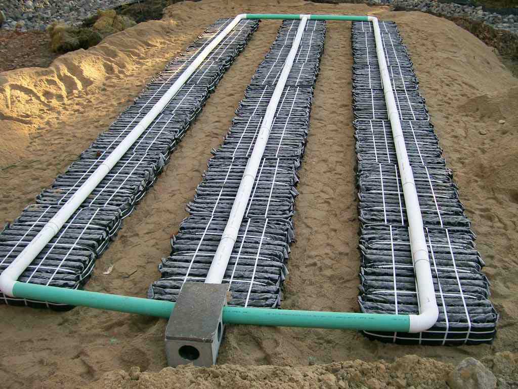 A perforated pipe is secured on top of the blocks to disperse wastewater onto and through them into the soil below